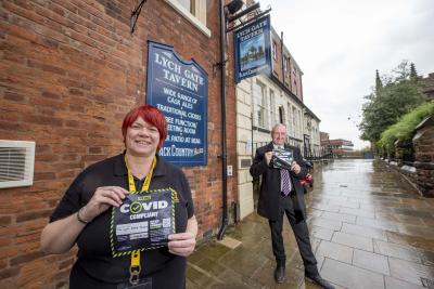 Councillor Steve Evans, cabinet member for city environment, presents Hayley Hall from Lich Gate Tavern in Wolverhampton City Centre with a Covid Compliant sticker