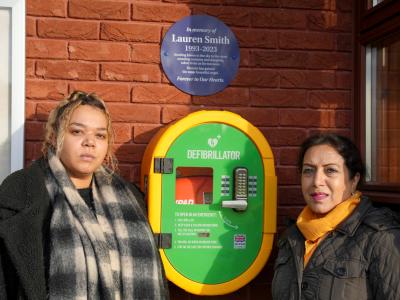 East Park Councillor Lovinyer Daley and Councillor Jasbir Jaspal, the City of Wolverhampton Council's Cabinet Member for Adults and Wellbeing, with the defibrillator which has been installed at East Park Library in memory of Lauren Smith, who tragically passed away last year aged just 29